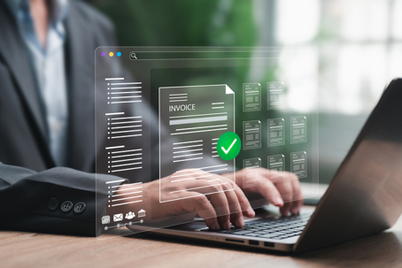 Professional reviewing digital invoices on a laptop to maintain accurate bookkeeping and prevent costly financial cleanup.