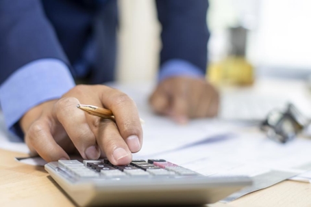 Close-up of a person calculating figures on a calculator.