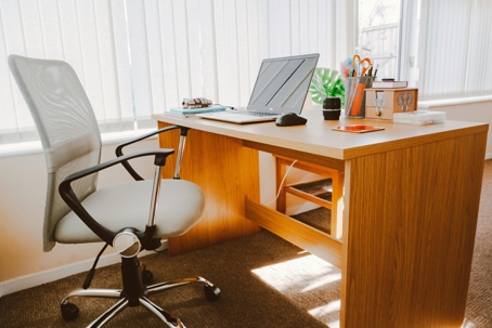 A clean office space is pictured with a computer on a wooden desk.